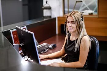 Coworking at 1330 Avenue of the Americas, New York, where the receptionist efficiently handles client inquiries.